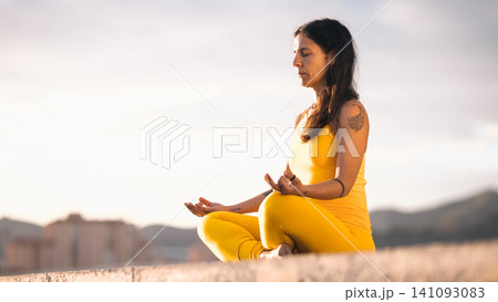 Woman meditating outdoor in lotus position practicing mindfulness Woman meditating outdoor in lotus position practicing mindfulness 141093083
