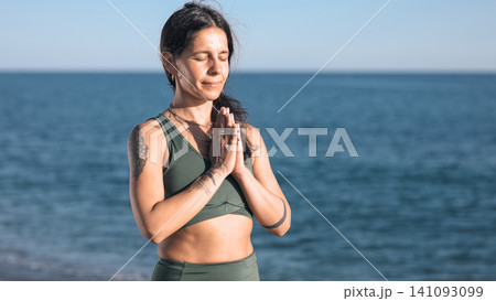 Woman meditating with hands in prayer pose on beach Woman meditating with hands in prayer pose on beach 141093099