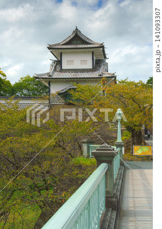 Kanazawa, Japan - Oct 6 2024, vertical view of Kanazawa Palace, with autumn foliage on trees in front of it and bridge with green railings and a lantern in foreground, on cloudy day, Kanazawa, Japan Kanazawa, Japan - Oct 6 2024, vertical view of Kanazawa Palace, with autumn foliage on trees in front of it and bridge with green railings and a lantern in foreground, on cloudy day, Kanazawa, Japan 141093307