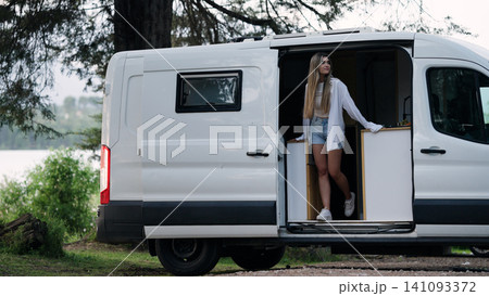 Woman enjoying nature next to camper van home 141093372