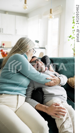 Mother kissing son with physical condition on couch Mother kissing son with physical condition on couch 141093462