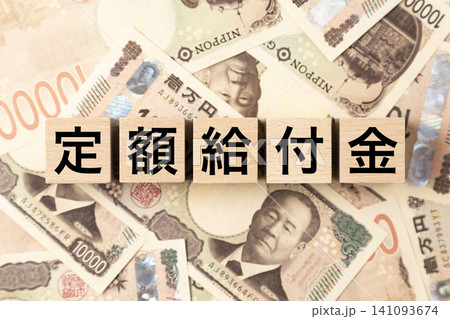 「定額給付金」と書かれたブロックとたくさんの一万円札 「定額給付金」と書かれたブロックとたくさんの一万円札 141093674