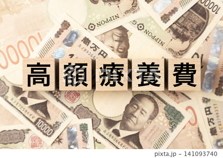 「高額療養費」と書かれたブロックとたくさんの一万円札 141093740