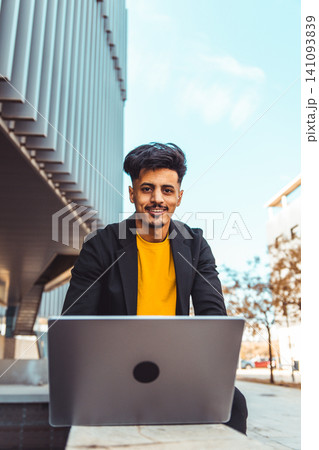 Moroccan man working on laptop outdoors smiling Moroccan man working on laptop outdoors smiling 141093839