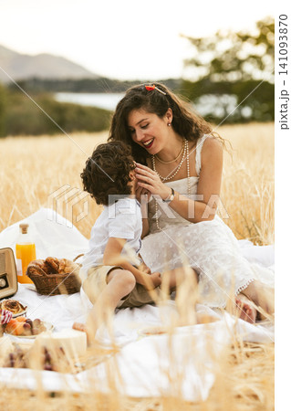 Mother and son enjoying picnic in golden wheat field 141093870