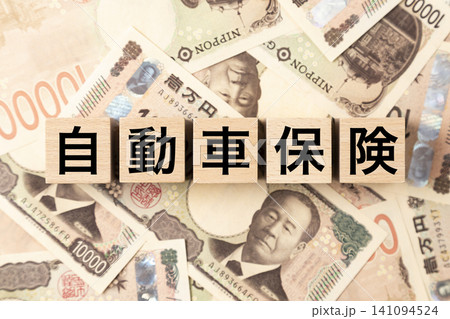 「自動車保険」と書かれたブロックとたくさんの一万円札 「自動車保険」と書かれたブロックとたくさんの一万円札 141094524