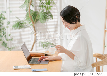 通帳を見て微笑む女性 通帳を見て微笑む女性 141095488