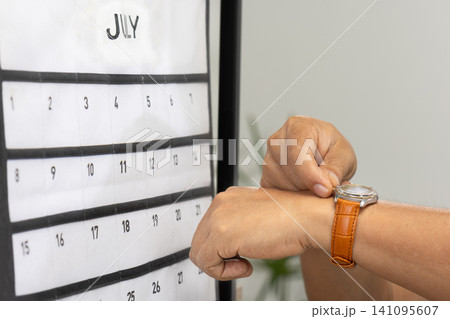 Senior Asian man with dementia struggles to set the time and day on his watch. Senior Asian man with dementia struggles to set the time and day on his watch. 141095607