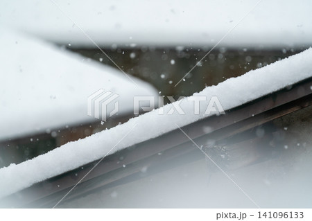 大雪が降る中で棟に積もった住宅屋根 大雪が降る中で棟に積もった住宅屋根 141096133