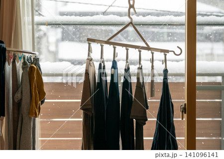 雪が降る窓際で連結ハンガーに並んだ洗濯物の部屋干しシーン 雪が降る窓際で連結ハンガーに並んだ洗濯物の部屋干しシーン 141096141