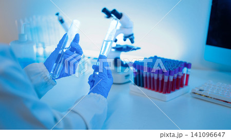 Laboratory Scientist Holding Test Tubes with Microscope and Blood Sample Rack in Medical Research Lab Laboratory Scientist Holding Test Tubes with Microscope and Blood Sample Rack in Medical Research Lab 141096647