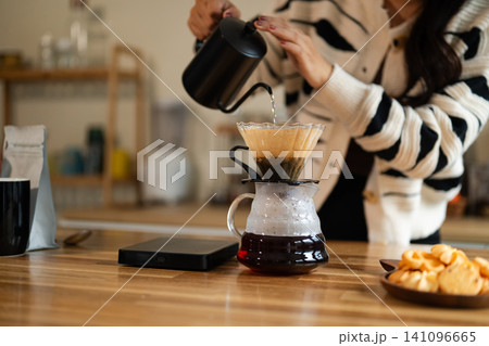 Woman Brewing Pour Over Coffee at Home Kitchen Counter with Gooseneck Kettle and Glass Carafe Woman Brewing Pour Over Coffee at Home Kitchen Counter with Gooseneck Kettle and Glass Carafe 141096665