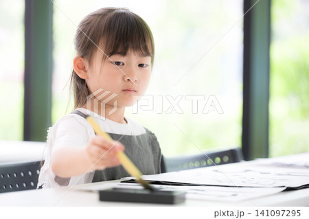 書道に集中して筆で文字を書く小学生の女の子・習字を学ぶ日本の子ども 真剣な表情 書道に集中して筆で文字を書く小学生の女の子・習字を学ぶ日本の子ども 真剣な表情 141097295