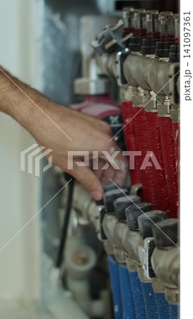 Vertical video Man hand adjusts the heat supply in the underfloor heating system. Vertical video Man hand adjusts the heat supply in the underfloor heating system. 141097361