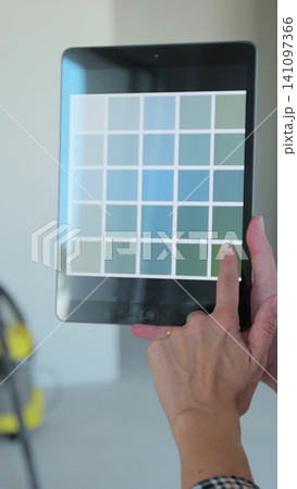 Vertical video Woman holding color set on tabletPC selecting paint for walls. Home, moving, decoration, renovation, and wall painting concept. Vertical video Woman holding color set on tabletPC selecting paint for walls. Home, moving, decoration, renovation, and wall painting concept. 141097366