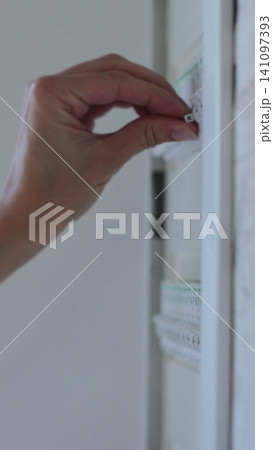 Vertical video Woman turns off the light on the electrical panel. Circuit breaker panel at home. Vertical video Woman turns off the light on the electrical panel. Circuit breaker panel at home. 141097393