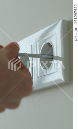 Vertical video Man hands of electrician dismantling old socket using screwdriver. Replacing electrical outlet. Installing. Repair. Electricity. Vertical video Man hands of electrician dismantling old socket using screwdriver. Replacing electrical outlet. Installing. Repair. Electricity. 141097420