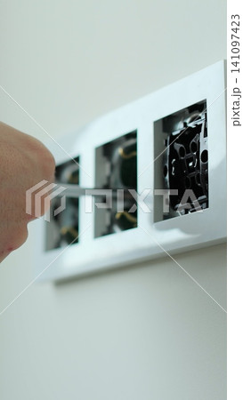 Vertical video Electrician installing a wall socket. Installing electrical wall outlets with a screwdriver in a new home. Vertical video Electrician installing a wall socket. Installing electrical wall outlets with a screwdriver in a new home. 141097423