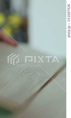 Vertical video Man kneeling and installing wood laminate floor in a home. Closeup on male hands. Vertical video Man kneeling and installing wood laminate floor in a home. Closeup on male hands. 141097426