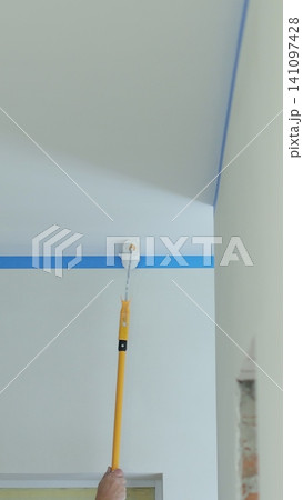 Vertical video Painting the ceiling white with the brush, repairing, reconstruction concept. Painting ceiling in white with a roller. Vertical video Painting the ceiling white with the brush, repairing, reconstruction concept. Painting ceiling in white with a roller. 141097428