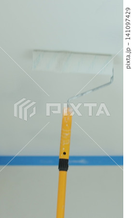 Vertical video Man painting the ceiling with white paint using a paint roller. Home repairs and finishing works. Vertical video Man painting the ceiling with white paint using a paint roller. Home repairs and finishing works. 141097429