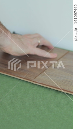 Vertical video Close-up of a man in an apartment laying laminate on the floor. Floor in a Home. Closeup on male hands. Vertical video Close-up of a man in an apartment laying laminate on the floor. Floor in a Home. Closeup on male hands. 141097440
