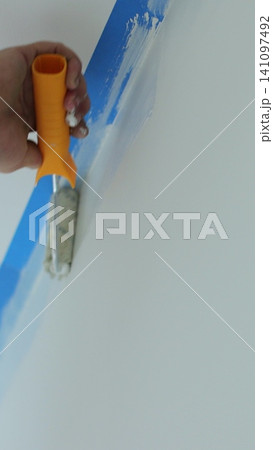 Vertical video Man worker hand painting the wall inside the house and building. Builder, tools, apartment renovation. 141097492