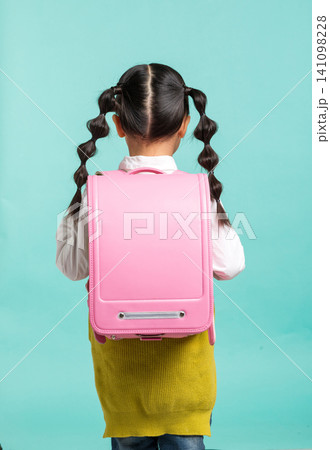 a female Asian student with a gourd-shaped braid and a pink backpack stands against a blue-green background themed around returning to school. a female Asian student with a gourd-shaped braid and a pink backpack stands against a blue-green background themed around returning to school. 141098228
