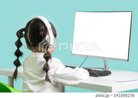 rear view of a young girl with pigtails sitting in front of a blank computer monitor. rear view of a young girl with pigtails sitting in front of a blank computer monitor. 141098236