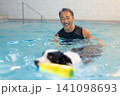 プールでリハビリをする犬とトレーナーのシニア男性 141098693