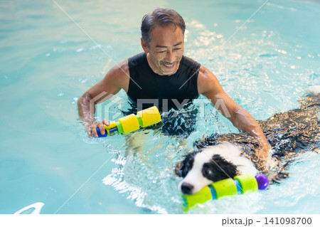 プールでリハビリをする犬とトレーナーのシニア男性 プールでリハビリをする犬とトレーナーのシニア男性 141098700