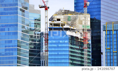 Crane on the construction site in a site surrounded by the high buildings. Office building under construction in the vicinity of high apartment buildings and office building. Crane on the construction site in a site surrounded by the high buildings. Office building under construction in the vicinity of high apartment buildings and office building. 141098707
