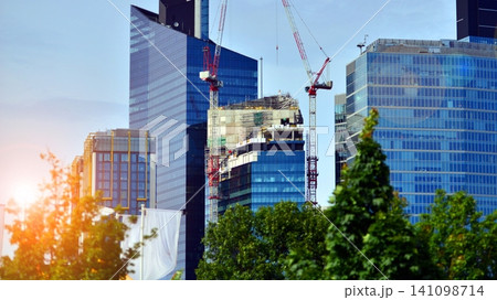 Crane on the construction site in a site surrounded by the high buildings. Office building under construction in the vicinity of high apartment buildings and office building. 141098714