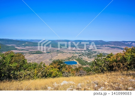 A small town at the foot of the mountains. ?illage in a valley between the mountains. Rural landscape. Wooden roofs of houses. Crimea A small town at the foot of the mountains. ?illage in a valley between the mountains. Rural landscape. Wooden roofs of houses. Crimea 141099083