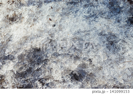 Small dirty broken ice on the ground. The beginning of spring. Broken ice on the ground as a background. Winter 141099153