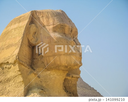 The head of the sphinx against the blue sky. Egypt. Cairo - Giza. View of sphinx from the Giza Plat The head of the sphinx against the blue sky. Egypt. Cairo - Giza. View of sphinx from the Giza Plat 141099210