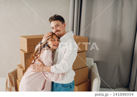 Happy young family couple man and woman hugging and moving with cardboard boxes to new estate home apartment. 141099354