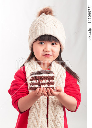 Little girl in winter outfit holding a slice of chocolate cake, dessert and birthday celebration concept. Little girl in winter outfit holding a slice of chocolate cake, dessert and birthday celebration concept. 141099774