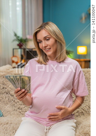 Pregnant woman counting dollars cash money planning budget for childbirth calm financial security 141100047