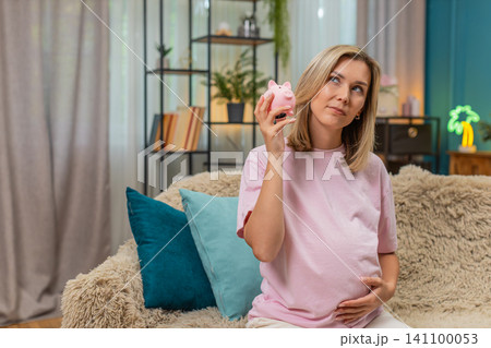 Pregnant woman shaking empty piggy bank sad planning budget dreaming improvement from poverty future Pregnant woman shaking empty piggy bank sad planning budget dreaming improvement from poverty future 141100053