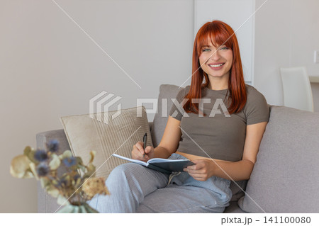 Young woman writes in notebook plans key decisions creates schedule and task list for next actions Young woman writes in notebook plans key decisions creates schedule and task list for next actions 141100080