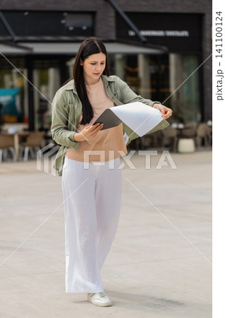 Young woman carrying documents walking in city street nervously rehearsing for job interview meeting Young woman carrying documents walking in city street nervously rehearsing for job interview meeting 141100124