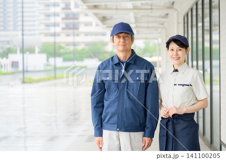 笑顔の作業服の男性と制服の女性（ビルメンテナンスイメージ） 141100205