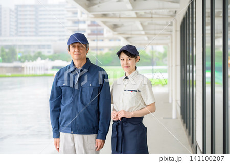 笑顔の作業服の男性と制服の女性(ビルメンテナンスイメージ) 笑顔の作業服の男性と制服の女性(ビルメンテナンスイメージ) 141100207