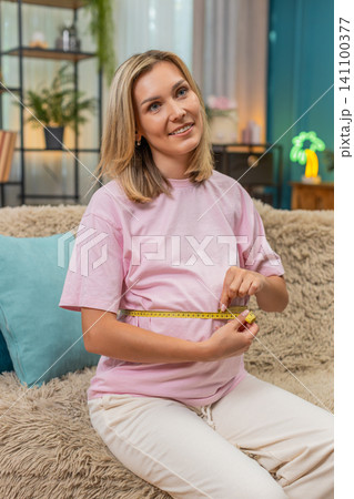Pregnant woman measuring belly with tape smiling satisfied with progress expecting baby birth soon Pregnant woman measuring belly with tape smiling satisfied with progress expecting baby birth soon 141100377