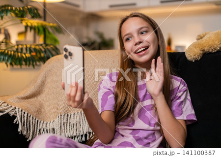 Teenager girl video call on smartphone tells school story to friend lively gesture smile active chat Teenager girl video call on smartphone tells school story to friend lively gesture smile active chat 141100387