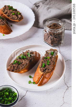 Crispy toasts with liver pate and chives on a plate on the table vertical view Crispy toasts with liver pate and chives on a plate on the table vertical view 141100588