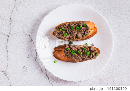 Close up of sandwiches with pork liver pate and green onions on a plate on the table top view Close up of sandwiches with pork liver pate and green onions on a plate on the table top view 141100590