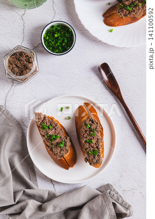 Crispy toasts with liver pate and chives on a plate on the table top and vertical view Crispy toasts with liver pate and chives on a plate on the table top and vertical view 141100592
