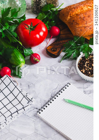 An open notebook and pencil, cucumbers, tomatoes, parsley, bread and spices on the table vertical view An open notebook and pencil, cucumbers, tomatoes, parsley, bread and spices on the table vertical view 141100627